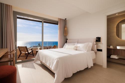 a bedroom with a bed and a view of the ocean at Little Crab Suites in Agios Gordios