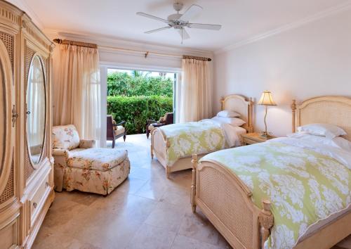 a bedroom with two beds and a chair and a window at Sweet Dreams in Saint James