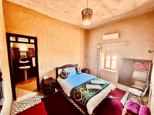 a bedroom with a bed and a sink in it at Les Roses Des Dunes in Merzouga