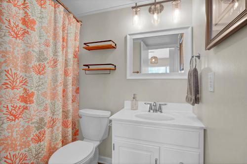 a bathroom with a toilet and a sink and a mirror at Seawind Sanctuary in Carolina Beach