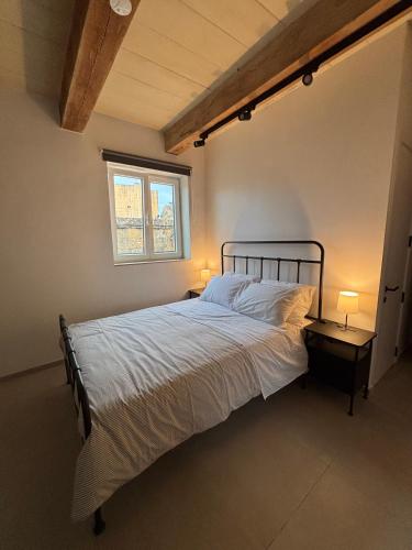 a bedroom with a bed and a window and two lamps at VillageStay in Rabat