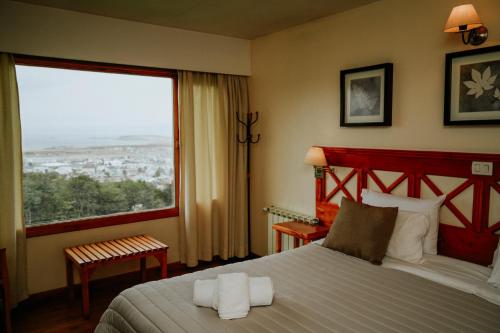 a bedroom with a bed and a large window at Altos Ushuaia Hotel & Resto in Ushuaia