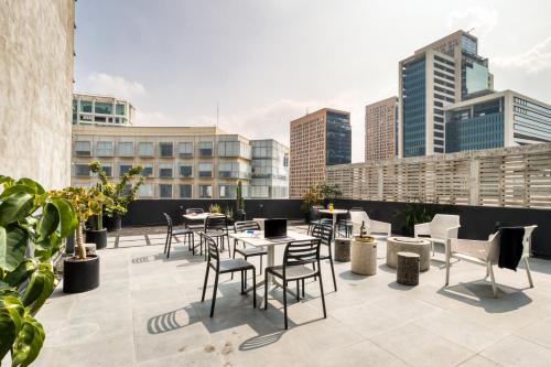 a rooftop patio with tables and chairs and buildings at ULIV Antara in Mexico City