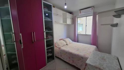 a small bedroom with a bed and a purple cabinet at Ilhéus Temporada in Ilhéus