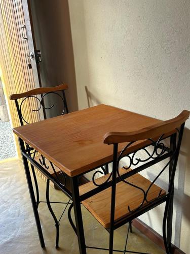 a wooden table and two chairs sitting next to a wall at Chalé da Janela in Lavras Novas