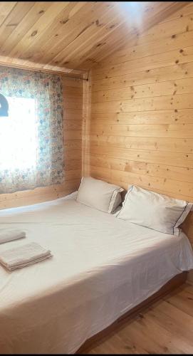 a large bed in a wooden room with a window at Zacisze 6 osobowy Domek nad jeziorem in Świętne