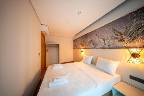 a bedroom with a large white bed with a painting on the wall at Hay Rezidans in Istanbul