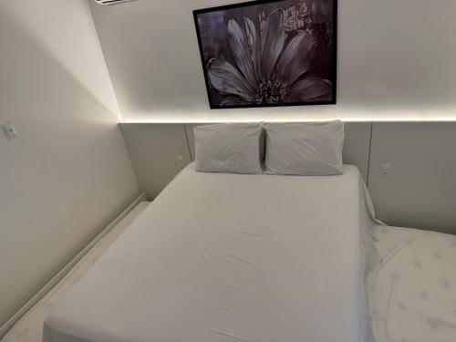 a white bed in a room with a picture on the wall at Flat Bugayalê Lounge in Garanhuns