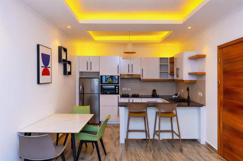 a kitchen with white cabinets and a table and chairs at T-Stone Apartments Hotels -Kigali in Kigali