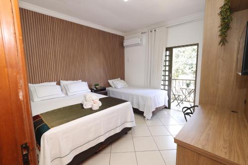 a hotel room with two beds with a stuffed animal on it at Pousada House Garden in Goiânia