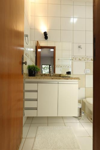 a white bathroom with a sink and a mirror at Pousada House Garden in Goiânia