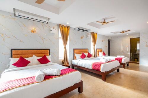 a bedroom with two beds with red and white pillows at White Forest - PV Hotels in Pondicherry