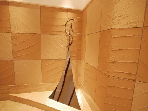 a bathroom with a wall with a mirror on it at Hotel Arstainn in Maizuru