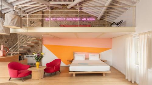 a bedroom with a bed and two red chairs at Mastrojanni Relais - Small Luxury Hotels of The World in Montalcino
