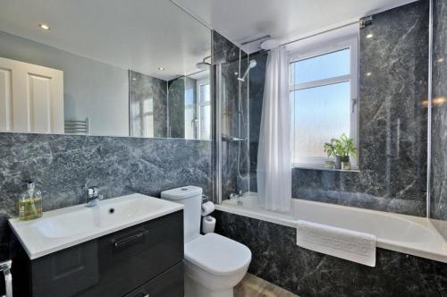 a bathroom with a sink and a toilet and a tub at Home from Home Aberdeen-Spacious West End Apartment-Free Parking-Near ARI & City Centre in Aberdeen