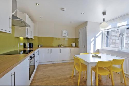 a kitchen with yellow chairs and a white table at Home from Home Aberdeen-Spacious West End Apartment-Free Parking-Near ARI & City Centre in Aberdeen