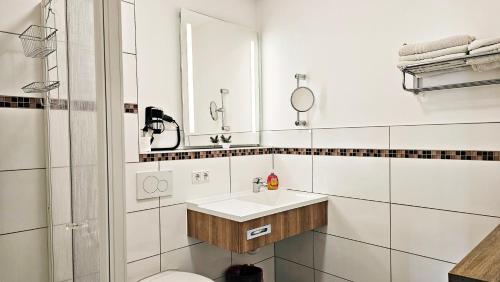a white bathroom with a sink and a mirror at Gasthof Alte Schule in Fürstenzell