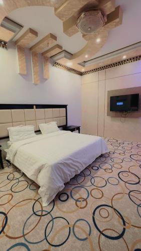 a bedroom with a large white bed and a tv at شقق مخدومه in Najran