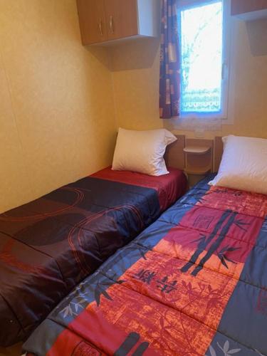 two beds sitting next to each other in a room at Mobile home Besse in Besse-et-Saint-Anastaise