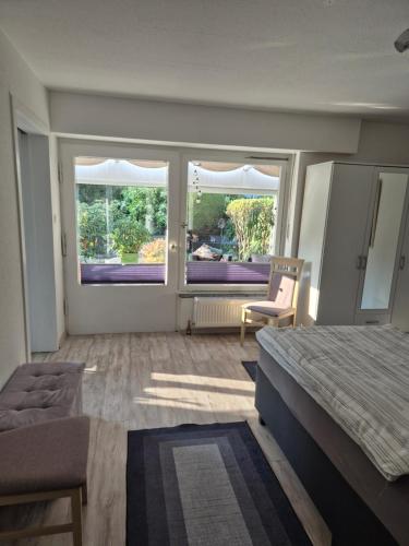 a bedroom with a bed and a chair and two windows at Evia Ferienwohnung in Heimbach