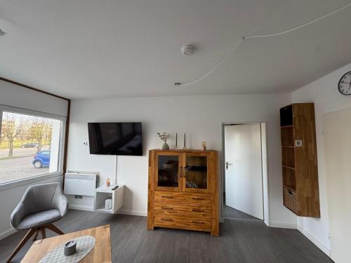 a living room with a tv and a wooden cabinet at Beachpoint-Fehmarn in Burgtiefe auf Fehmarn 