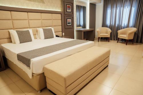 a bedroom with a large bed and chairs in it at Hospedare Hotel in Marechal Cândido Rondon