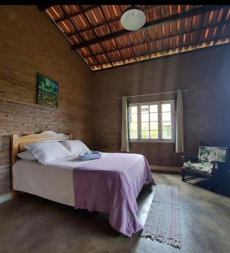 a bedroom with a bed and a brick wall at Chalé Guaíras in Mulungu