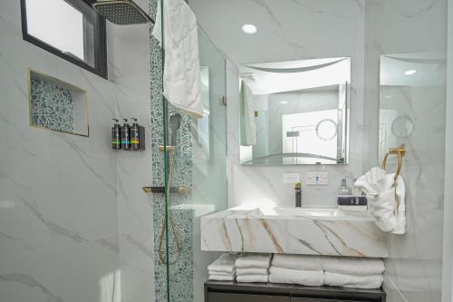a bathroom with a sink and a shower with towels at Golden Pear Villa-MSV 10BR - 5 Fully Equipped Kitchens, Harbor & Sea Views in Morne Longue