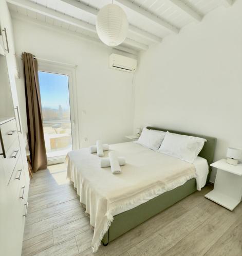 a white bedroom with a large bed and a window at Villa Greystone & Sky Mykonos in Tourlos