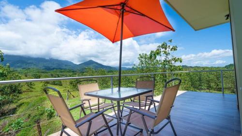 a table and chairs on a balcony with an umbrella at Villa Kiskadee - Beautiful Mountain Views with Private Pool in Quepos