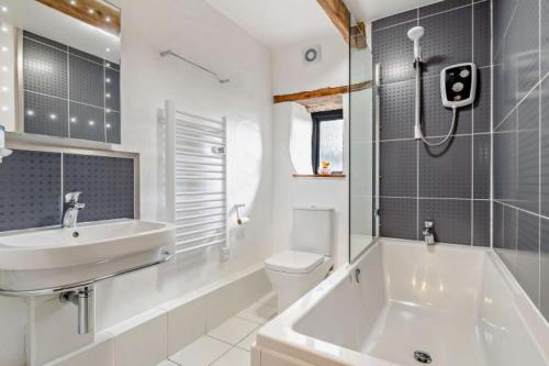 a bathroom with a sink and a tub and a toilet at Nuthatch Cottage in Cardinham