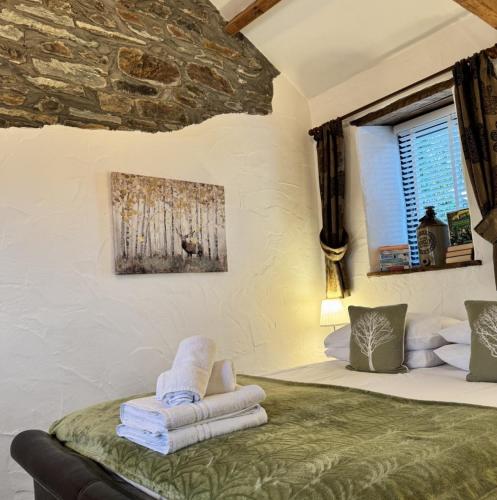 a bedroom with a bed with towels and a window at Nuthatch Cottage in Cardinham
