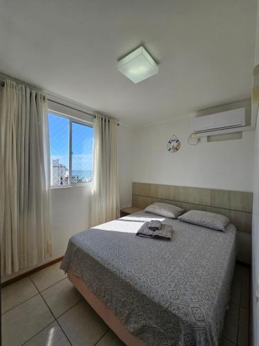 a bedroom with a bed and a large window at Apto.napraia BEACH 901 em Piçarras com vista mar in Piçarras