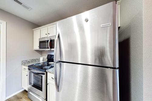 a stainless steel refrigerator in a kitchen with white cabinets at Vineyards 2909 #3 in Branson