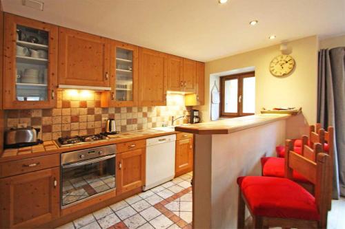 une cuisine avec des placards en bois et un comptoir avec des chaises rouges dans l'établissement La Ferme des Praz apartment - Chamonix All Year, à Chamonix-Mont-Blanc