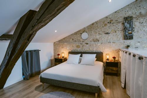 a bedroom with a bed and a stone wall at Le Loft - Classé 5 ÉTOILES in Mussidan