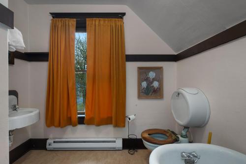 a bathroom with a toilet and a sink and a window at McCleary Hotel in McCleary
