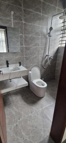 a bathroom with a toilet and a sink and a shower at The white house in Douala