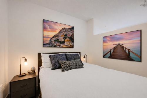a bedroom with a white bed and a painting on the wall at Chic & Modern Apartment In The Heart Of Downtown in Victoria