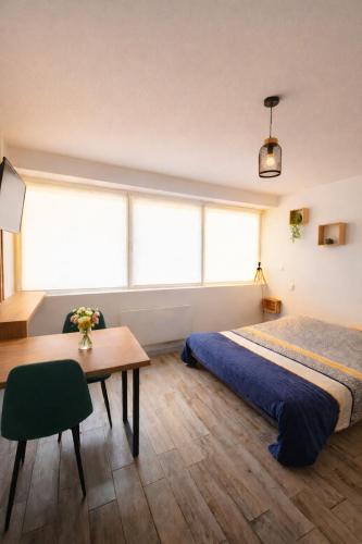 a bedroom with a bed and a table and windows at Chez Coco - Studio à 200m de la Gare ! in Besançon