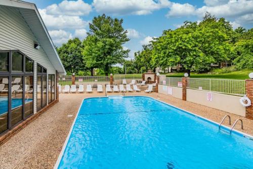 a swimming pool with chairs and a house at Thousand Hills - Family Getaway in Branson