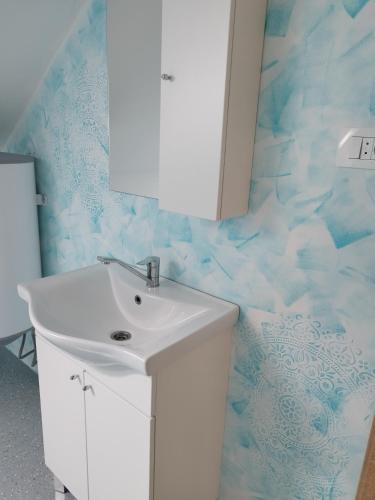 a bathroom with a white sink and blue wallpaper at Apartmani Bele breze in Adlešiči