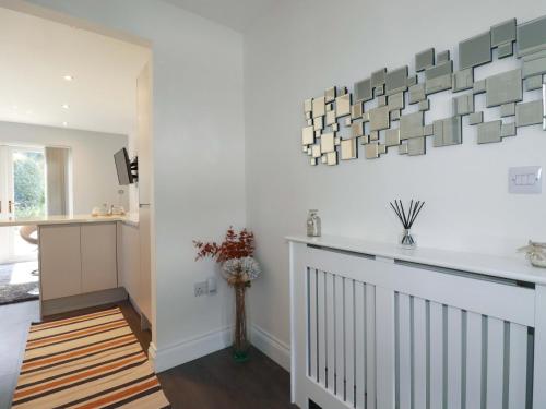 a hallway with white walls and a vase with flowers at Little Pippin in Carlyon Bay