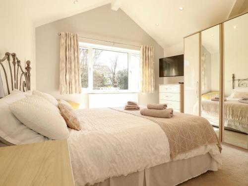 a white bedroom with a large bed and a window at Little Pippin in Carlyon Bay