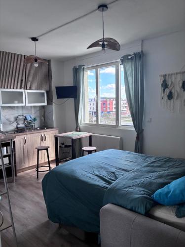 ein Schlafzimmer mit Bett und Schreibtisch sowie eine Küche in der Unterkunft Studio Aloe in Dunkerque