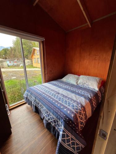 a bed in a room with a large window at Cabañas Villegas C2 in Hornopiren