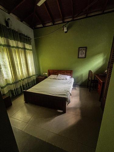 a bedroom with a bed in a green wall at Tea Estate Villa in Ratnapura