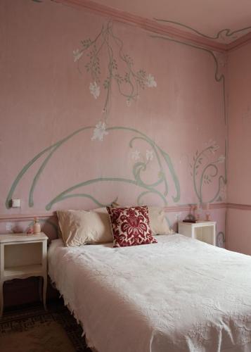 a bedroom with a white bed with a pink wall at La Maison Tataouine in Moux
