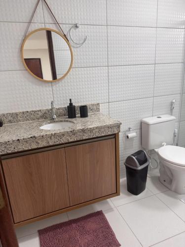 a bathroom with a sink and a mirror and a toilet at Refúgio Cachoeira Guaibim in Guaibim