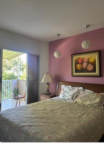 a bedroom with a bed and a painting of flowers on the wall at Refúgio Aconchegante com Varanda para Natureza in Resende